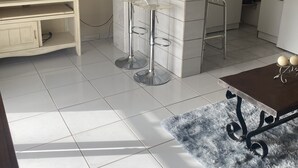 Een moderne keuken met witte kasten, een inbouw eiland en een flatscreen televisie op een standaard.