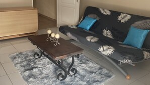 Een woonkamer met een bank, salontafel, houten kast en een deur.
