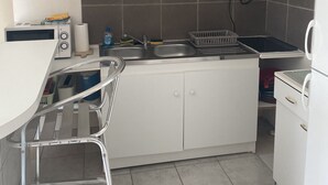 Een kleine keuken met witte kastjes, een roestvrijstalen spoelbak en een ingebouwde magnetron.