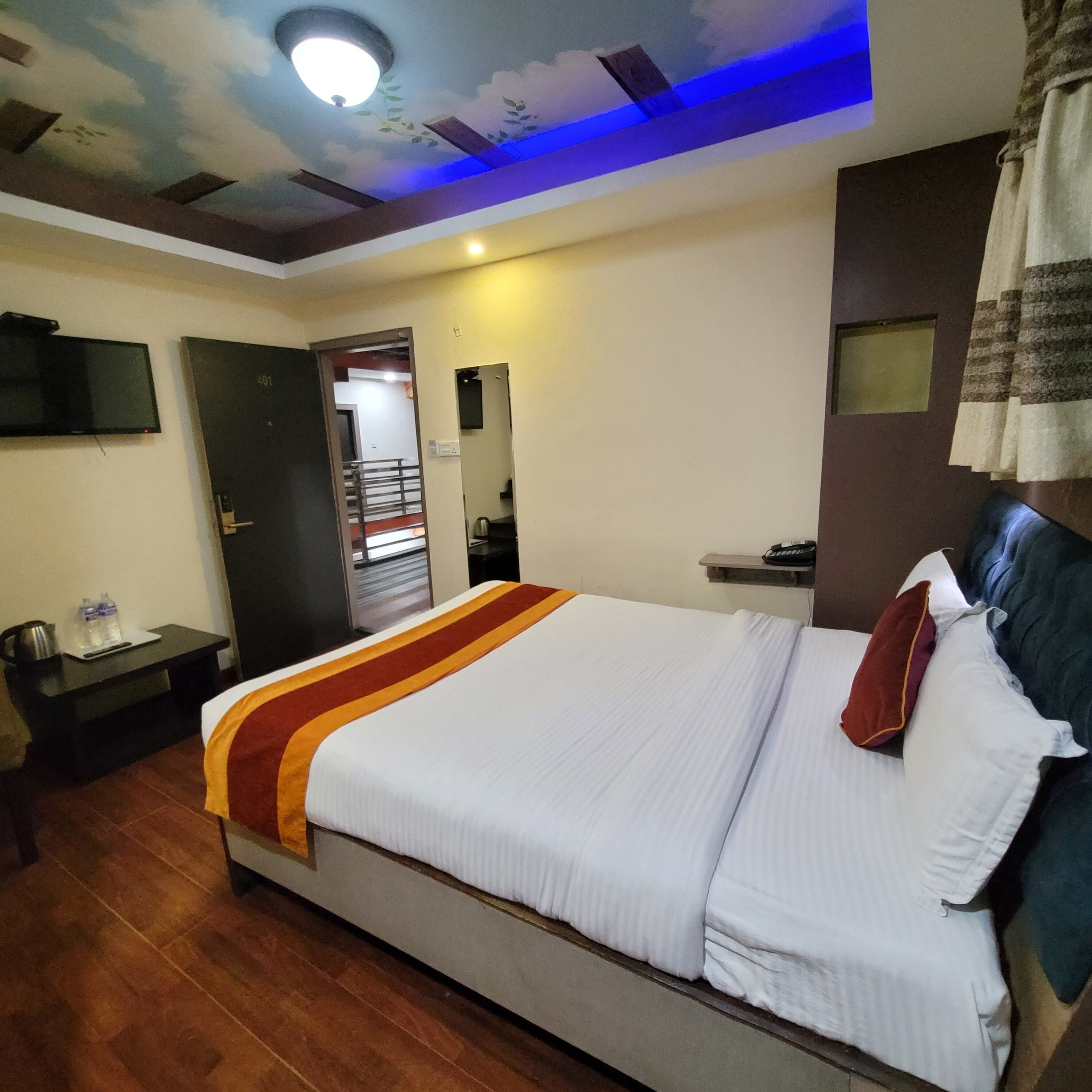 A hotel room with a bed, a desk, a TV, and a ceiling with a light fixture.