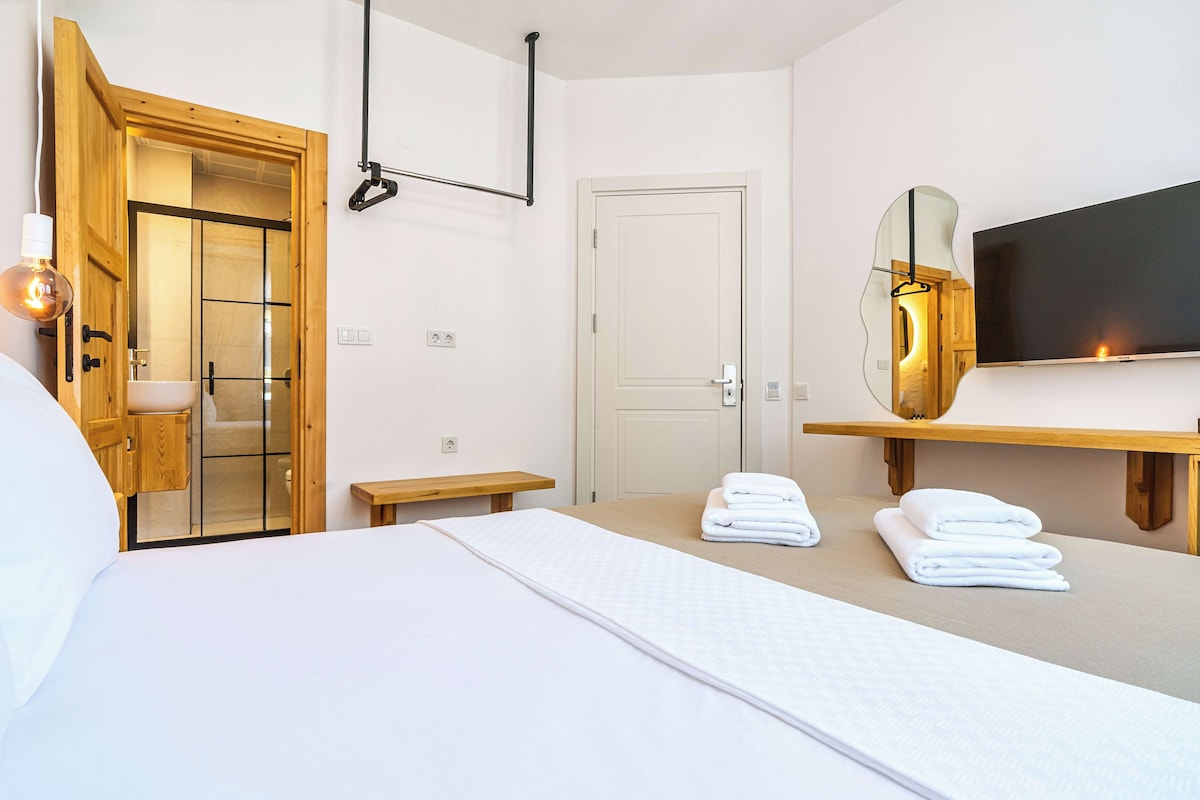 Habitación de hotel con una cama, una puerta de madera, un televisor y un espejo.
