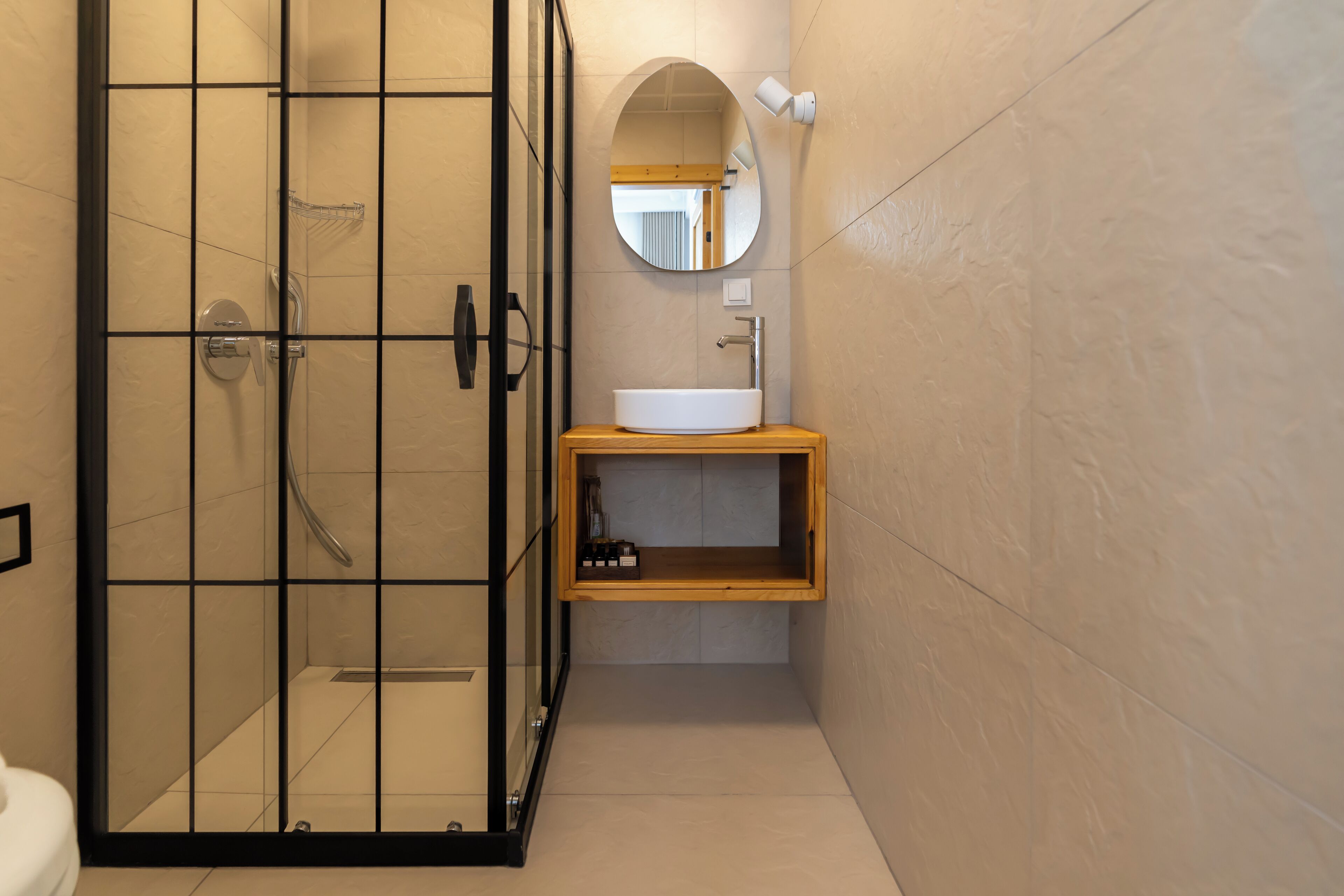 A bathroom with a glass-enclosed shower, a wooden vanity with a sink, and a mirror above the vanity.