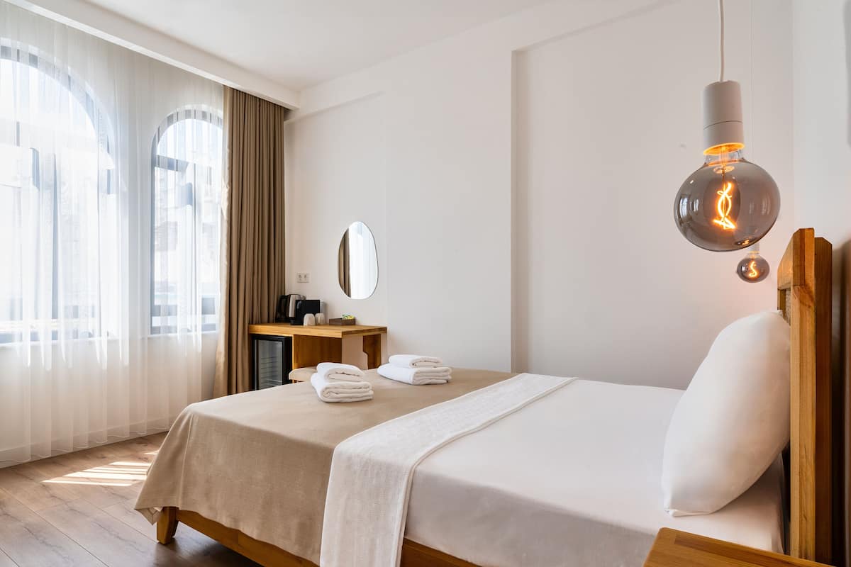 A hotel room with two beds, a desk with a mirror, and a hanging light fixture.
