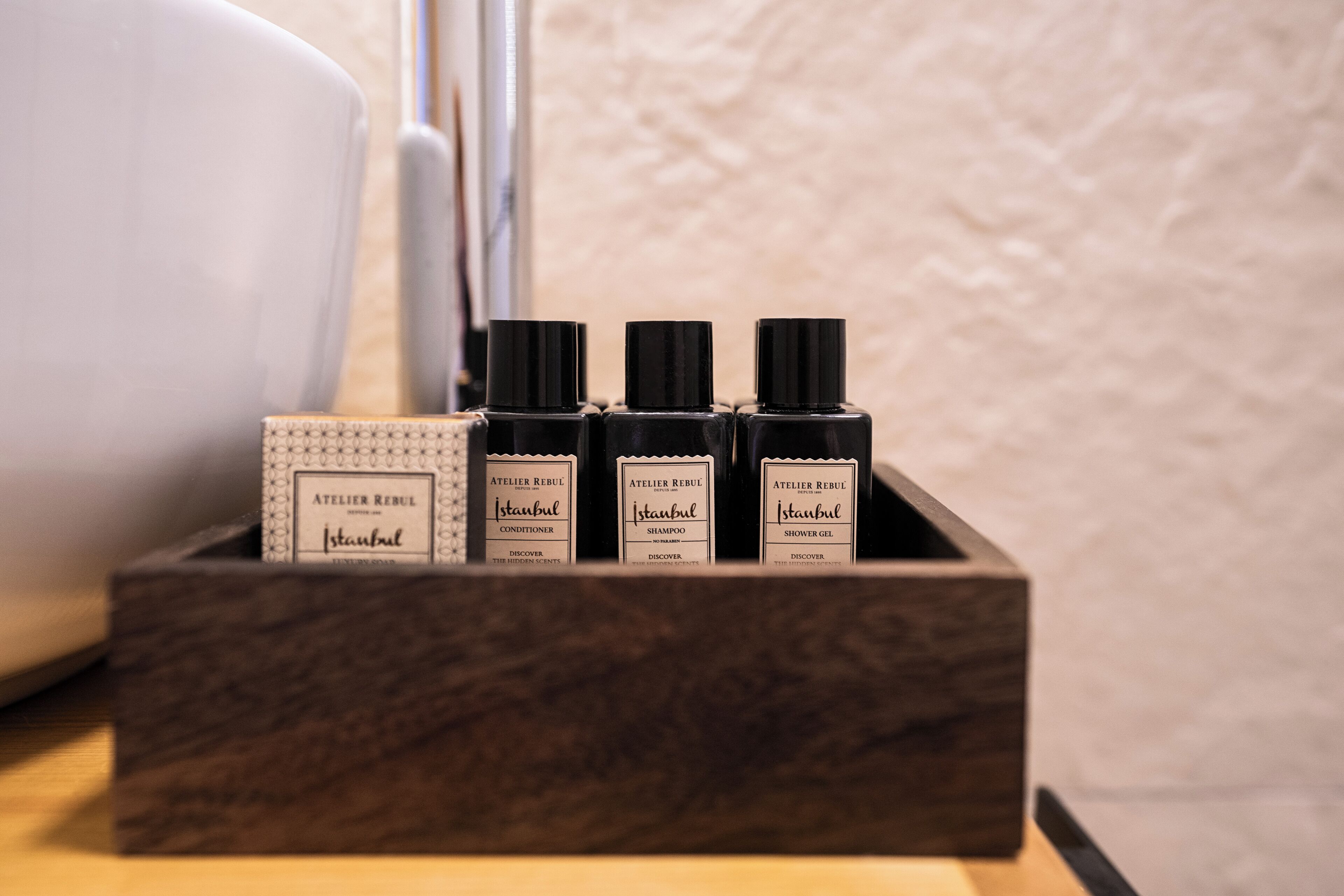 A wooden box containing four bottles of Istanbul-based shower gel, conditioner, and shampoo.