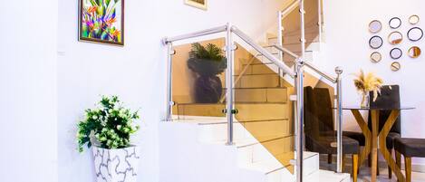 A modern interior with a staircase, a dining area with a table and chairs, and decorative wall art.