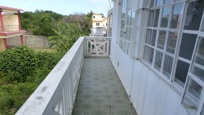A narrow corridor with patterned floor tiles, white railings, and large windows. - Appartement privatif ou location de chambres - Villa Lotus Paradise (Calodyne)