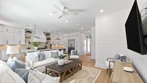 A modern living room with a sofa, coffee table, and TV. - The Blue Pearl at Grayton|Golf Cart to Beach|Private Pool (Santa Rosa Beach)