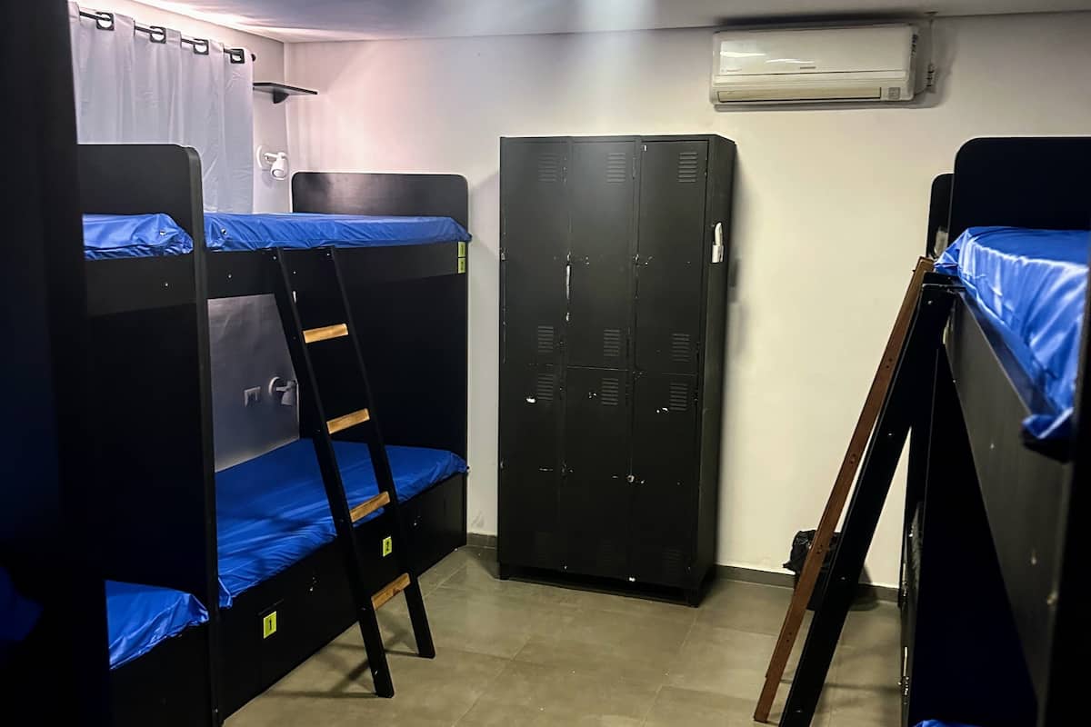 A dormitory room with bunk beds, a wardrobe, and an air conditioning unit.