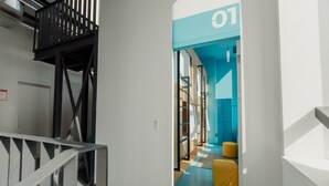 A modern interior with a staircase, a blue accent wall, and a yellow ottoman. - ElevenplusOne (Dilijan)