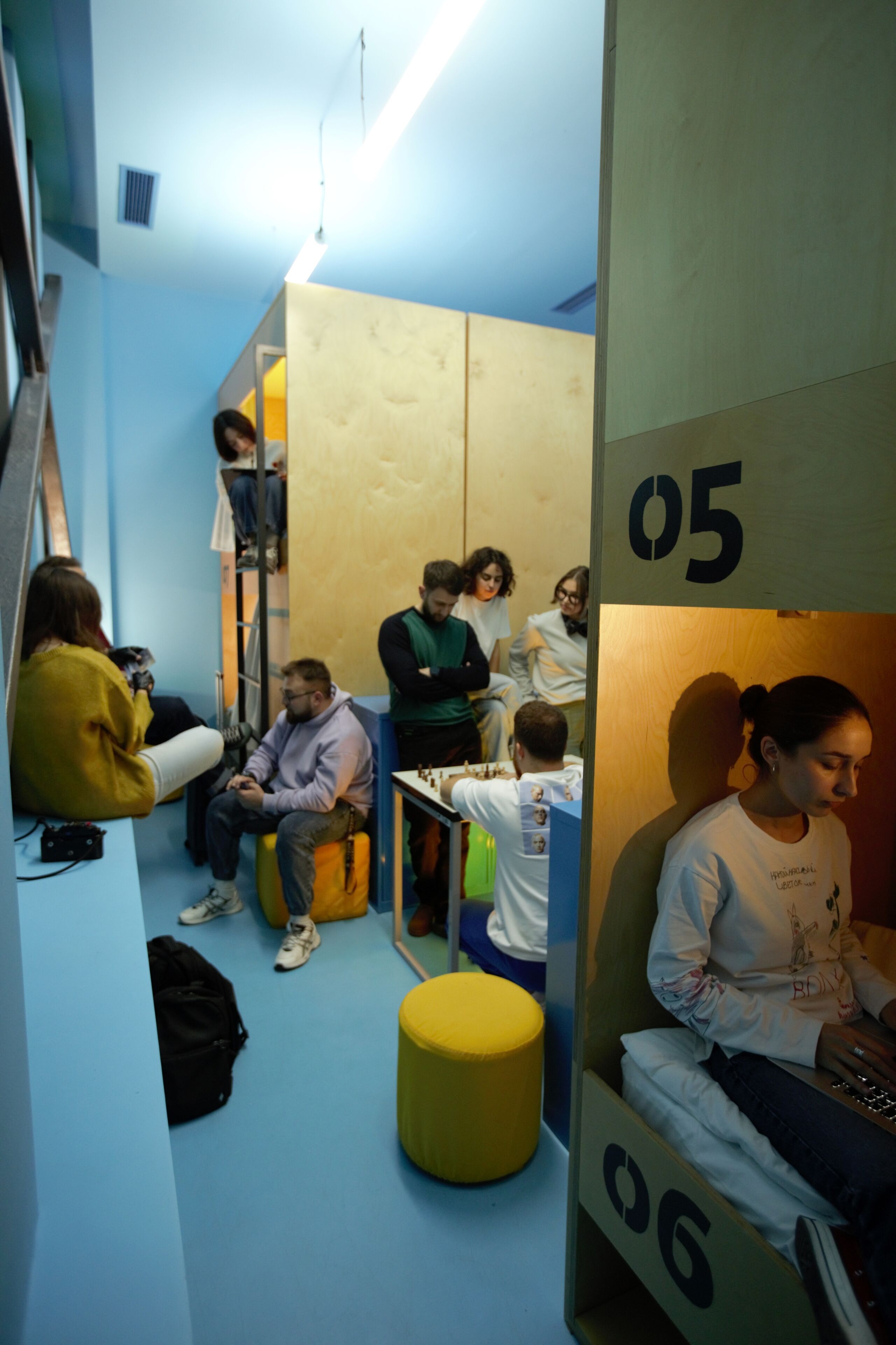 A room with bunk beds, a desk, and a yellow ottoman.