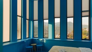 A room with large windows, a bed, two chairs, and a small table. - ElevenplusOne (Dilijan)