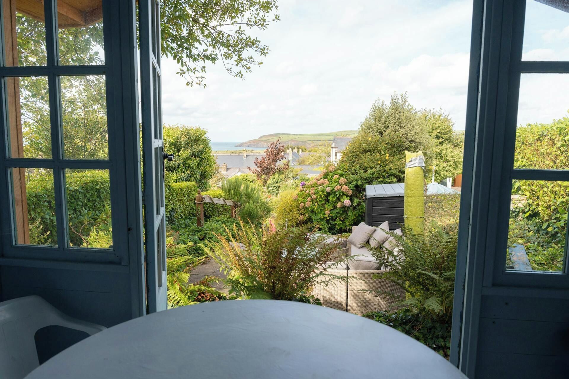 A room with a large window overlooking a garden and a view of the sea.