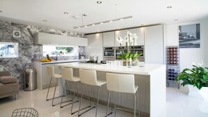 A modern kitchen with a marble backsplash, stainless steel appliances, and a central island with bar stools. - Morawel, St Dogmaels (Saint Dogmaels)
