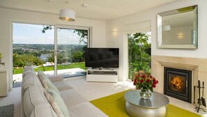 A modern living room with a sofa, TV, fireplace, and a view of the outdoors. - Morawel, St Dogmaels (Saint Dogmaels)