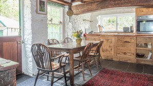 Eine rustikale Küche mit Holzsäulen, einem Esstisch mit Stühlen und einem großen Fenster.