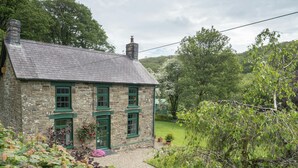 Ein Haus aus Stein mit grünen Fenstern und einer Auffahrt mit Kies.