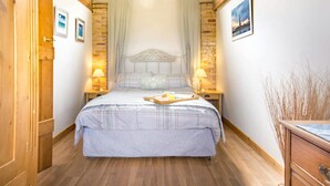 A bedroom with a bed, wooden walls, a skylight, and a wooden door. - Cinnamon Cottage, Newcastle Emlyn (Felindre)