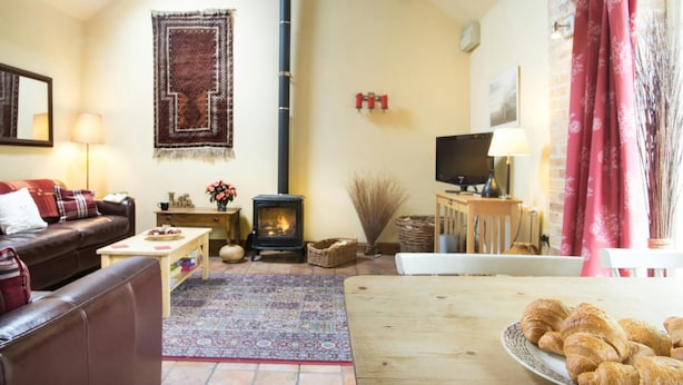 A cozy living room with a fireplace, leather sofa, and a table with pastries. - Cinnamon Cottage, Newcastle Emlyn (Felindre)