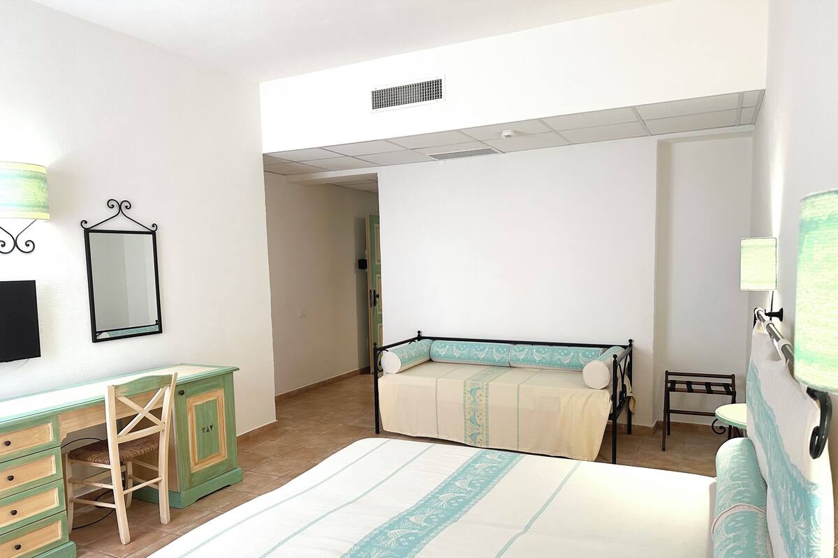 A bedroom with a bed, a desk, a chair, and a wardrobe.