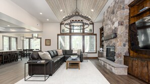 A spacious living area with a stone fireplace, a large sectional sofa, and a wooden coffee table. - Mirror Rock Retreat with Access to Exclusive Golf (Bend)