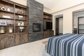 Une chambre moderne avec un grand lit, des étagères en bois, une cheminée et un téléviseur.