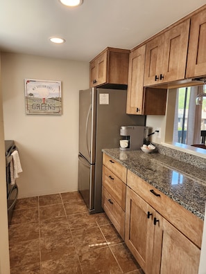 A compact kitchen with wooden cabinets, a stainless steel refrigerator, and a granite countertop. - Newly renovated, Enjoy the beautiful Fall Weather in the South!! (Pinehurst)
