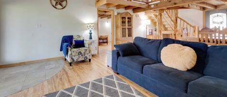A spacious living room with a blue sofa, wooden flooring, a staircase, and a star wall decoration.