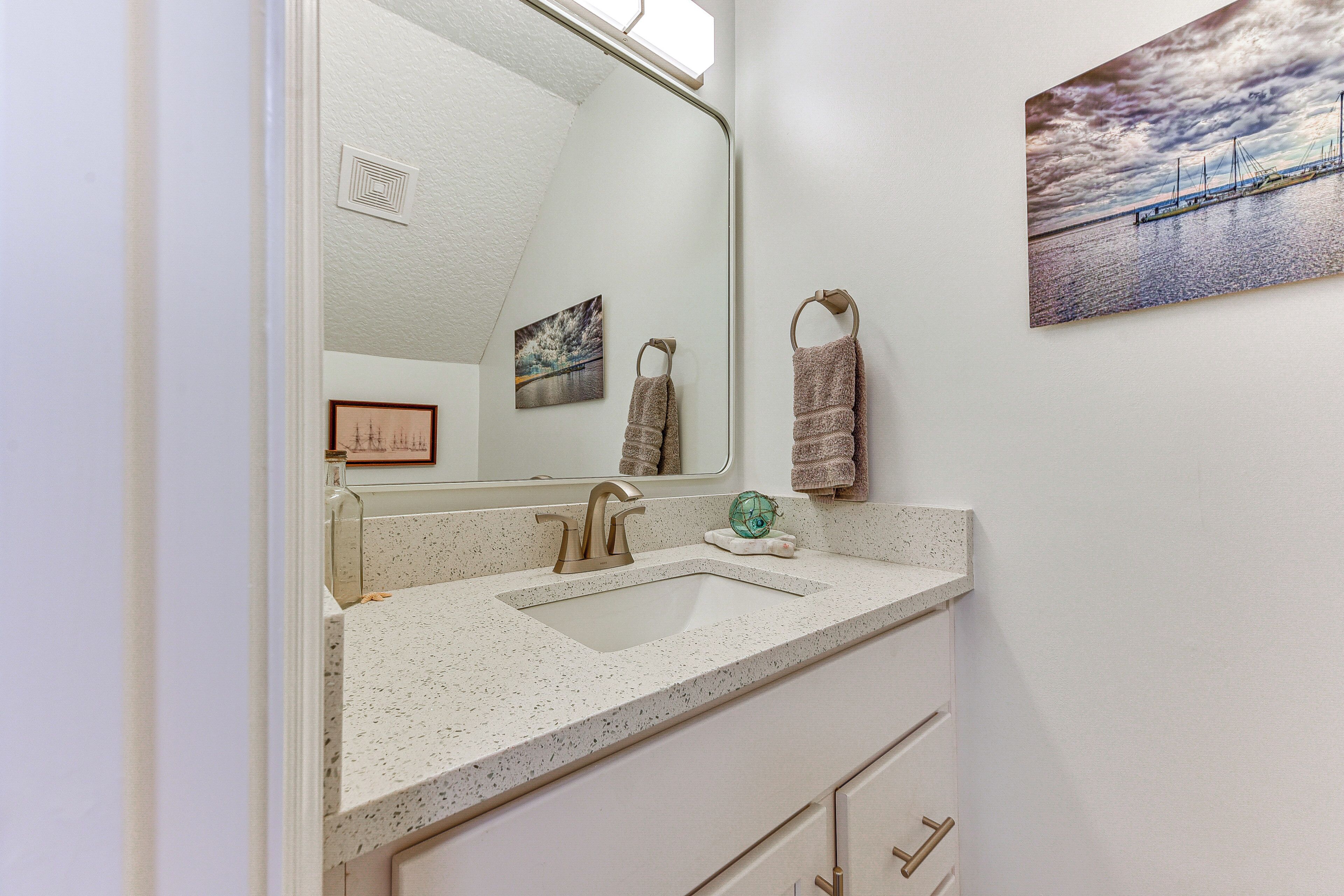 A bathroom with a large mirror, a sink, and a towel rack.