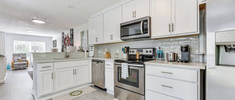 A modern kitchen with white cabinets, stainless steel appliances, and a dishwasher.