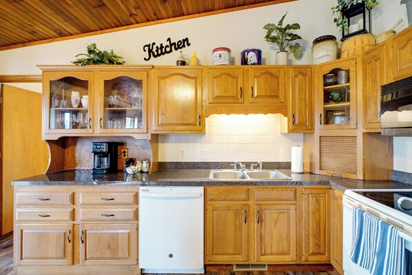 A kitchen with wooden cabinets, a dishwasher, a sink, and a stove.