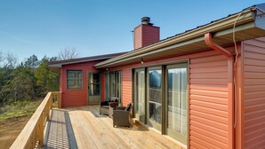 A red house with a wooden deck, large sliding glass doors, and a chimney.