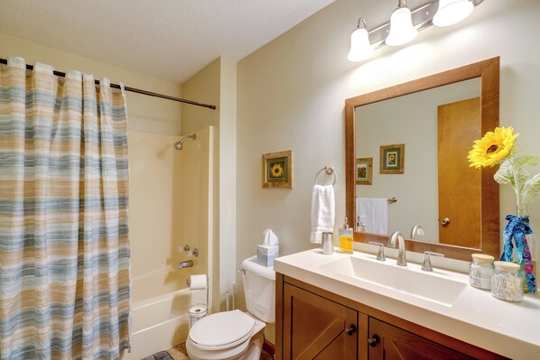 A bathroom with a shower, toilet, sink, and mirror.