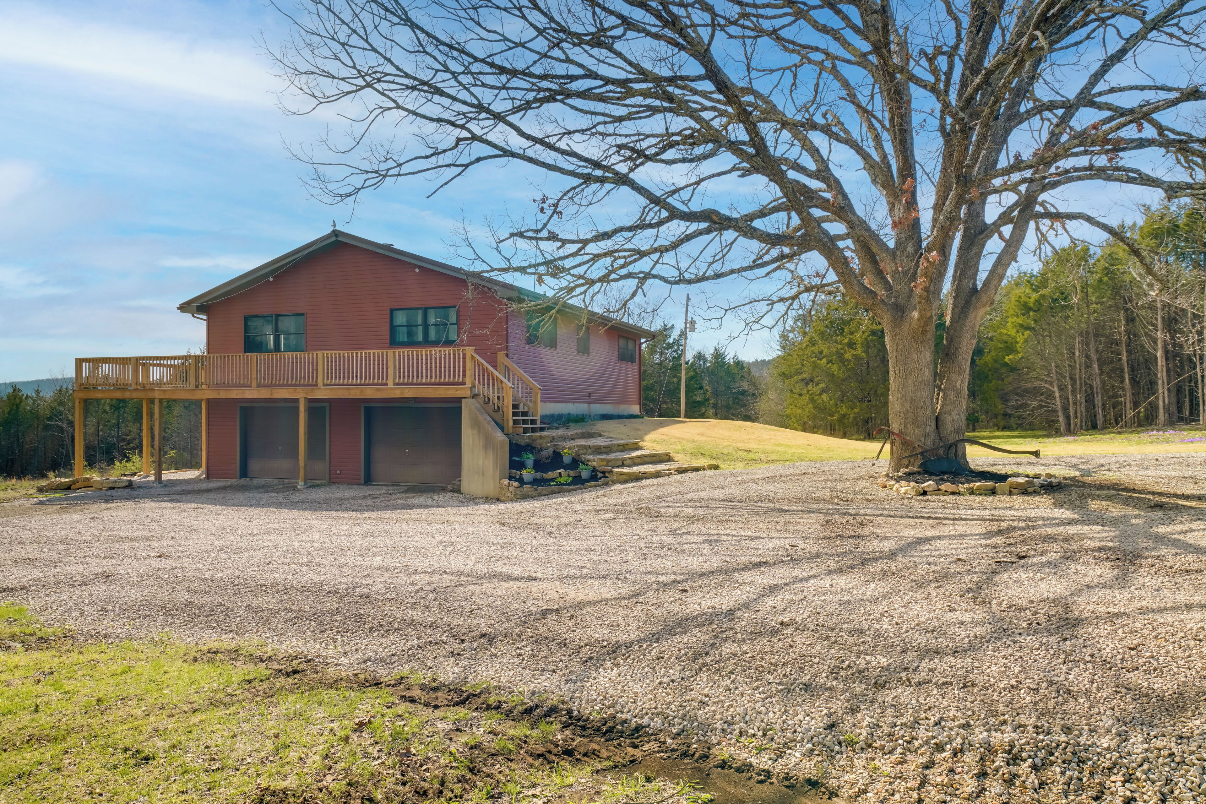 A two-story house with a wooden deck and a gravel driveway.