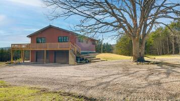 A two-story house with a wooden deck and a gravel driveway.