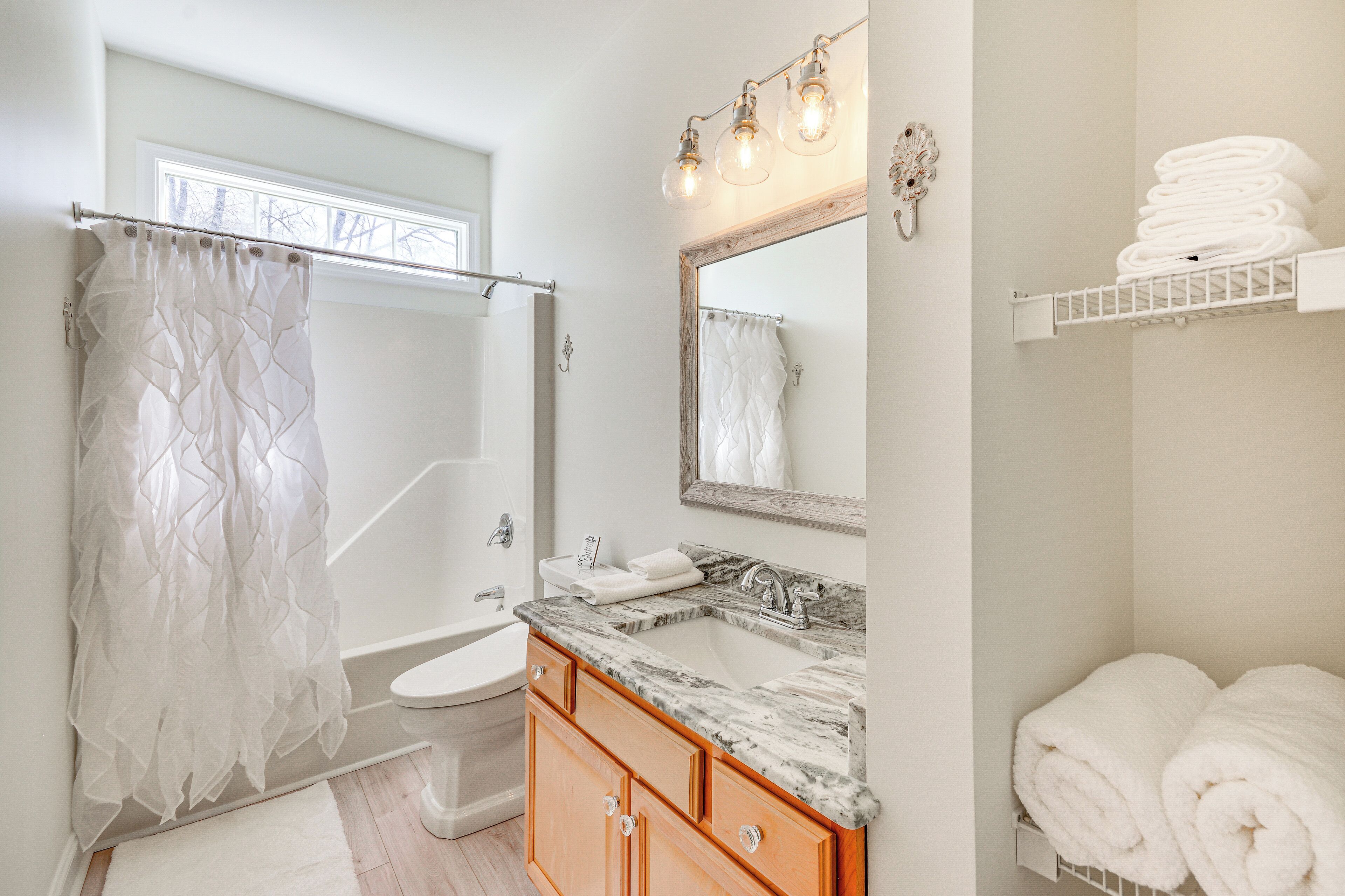A bathroom with a shower curtain, a sink with a mirror, and a towel rack.