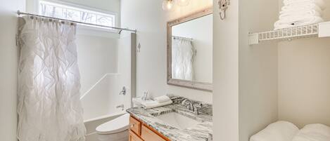 A bathroom with a shower curtain, a sink with a mirror, and a towel rack.