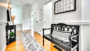 A hallway with a bench, a rug, and framed botanical prints on the wall. - Bright & Elegant Home in High Point w/ Deck! (High Point)