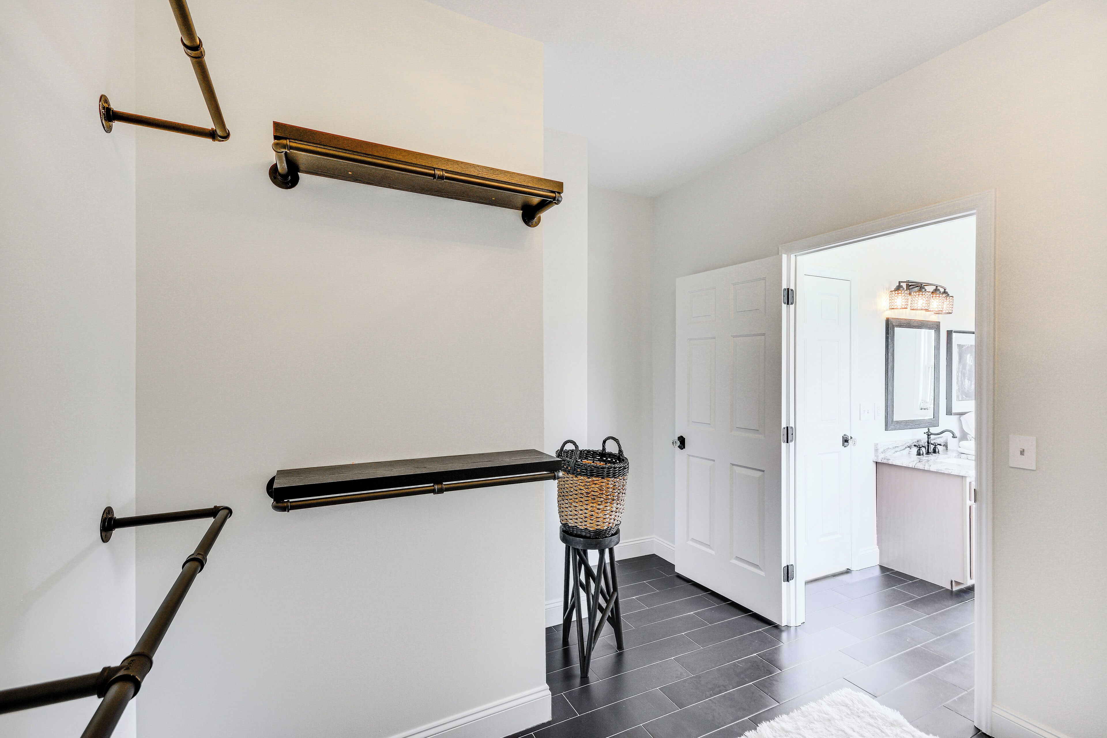 A hallway with a black floor, white walls, and a white door at the end.