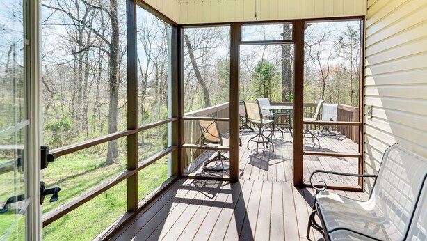 A covered deck with a table and chairs, large windows, and a ceiling fan. - Bright & Elegant Home in High Point w/ Deck! (High Point)