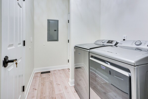 A laundry room with a front-loading washing machine, a door with a key in the lock, and a small electrical panel on the wall. - Bright & Elegant Home in High Point w/ Deck! (High Point)