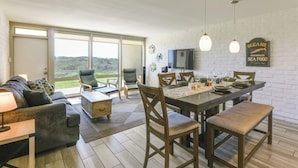 Ein modernes Wohnzimmer mit Essbereich, großen Fenstern und Blick ins Freie.