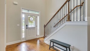 A hallway with a wooden staircase, a bench, and a door with a window. - Spacious Aiken Home ~ 8 Mi to Downtown! (Aiken)