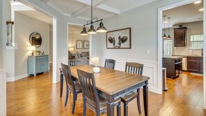 A dining area with a wooden table and chairs, a chandelier, and a painting on the wall. - Spacious Aiken Home ~ 8 Mi to Downtown! (Aiken)