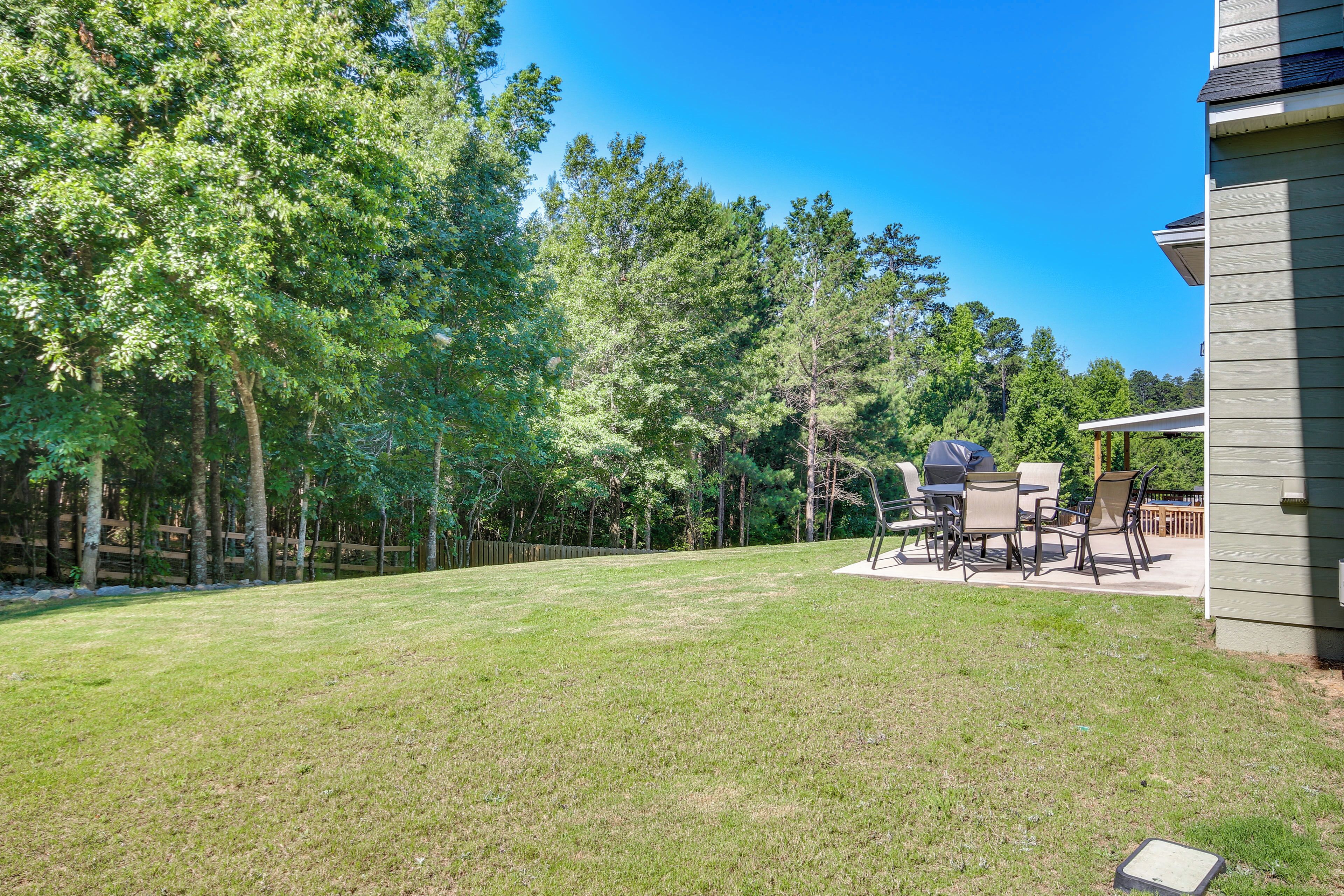 A backyard with a patio area, outdoor furniture, and a wooden fence.