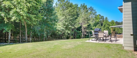A backyard with a patio area, outdoor furniture, and a wooden fence.