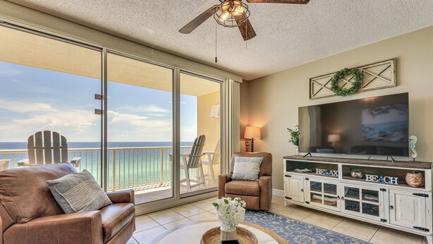 A spacious living room with a large TV, comfortable seating, and a view of the ocean. - Beachfront Panama City Beach Condo w/ Outdoor Pool (Panama City Beach)