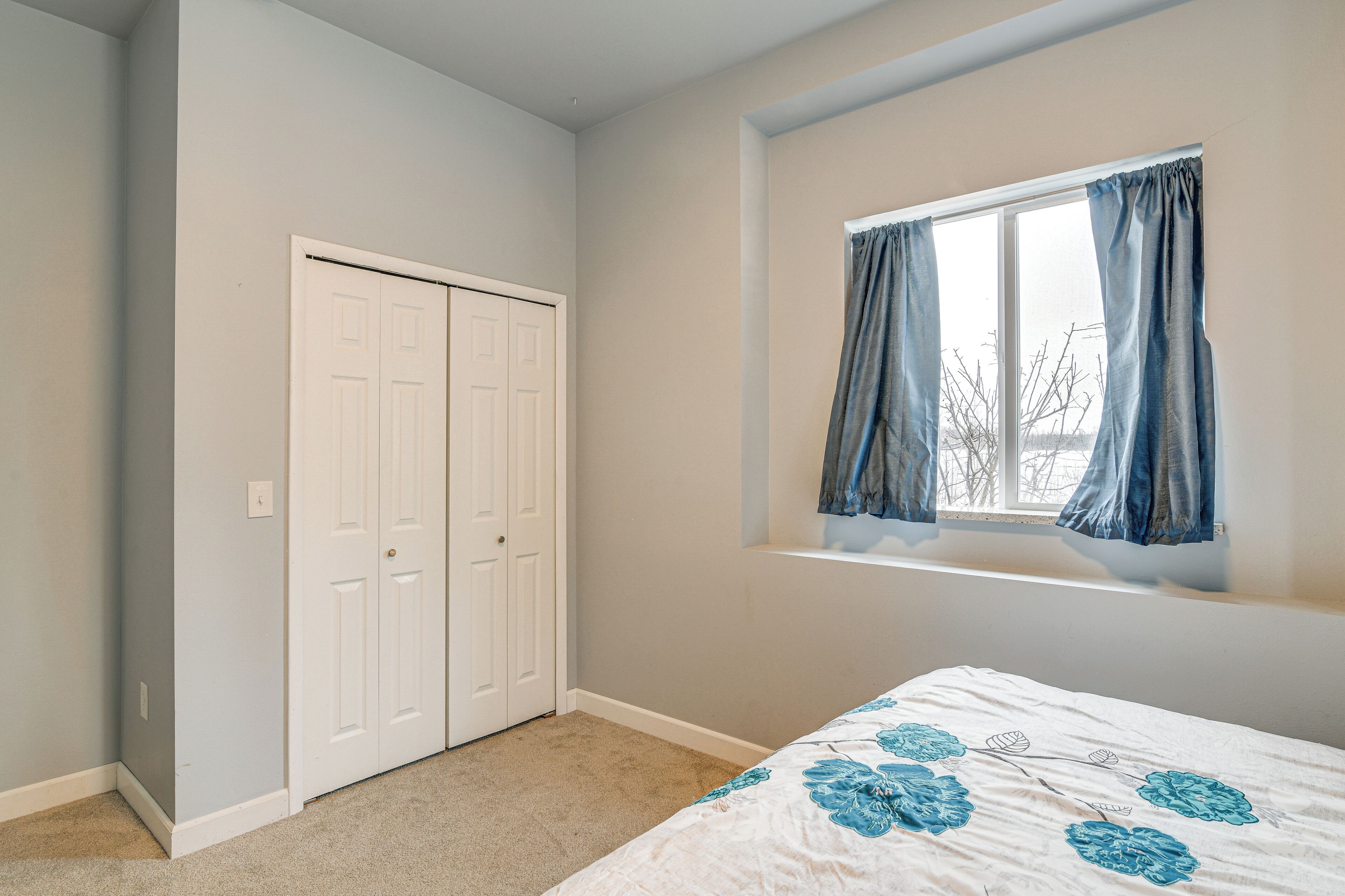 A bedroom with a bed, a window with curtains, and a closet.