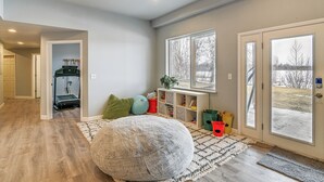 Ein geräumiger Raum mit einem großen Sitzsack, einer Spielecke mit Spielzeug und Blick durch die Tür.