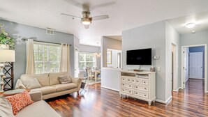 A living room with a sofa, TV, and wooden flooring. - Community Pool & Private Balcony: Chic Lewes Gem (Rehoboth Beach)
