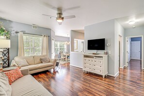 A spacious living room with a beige sofa, a white entertainment center, and hardwood flooring. - Community Pool & Private Balcony: Chic Lewes Gem (Rehoboth Beach)